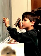 Žák píšící na tabuli - výuka soukromé školy